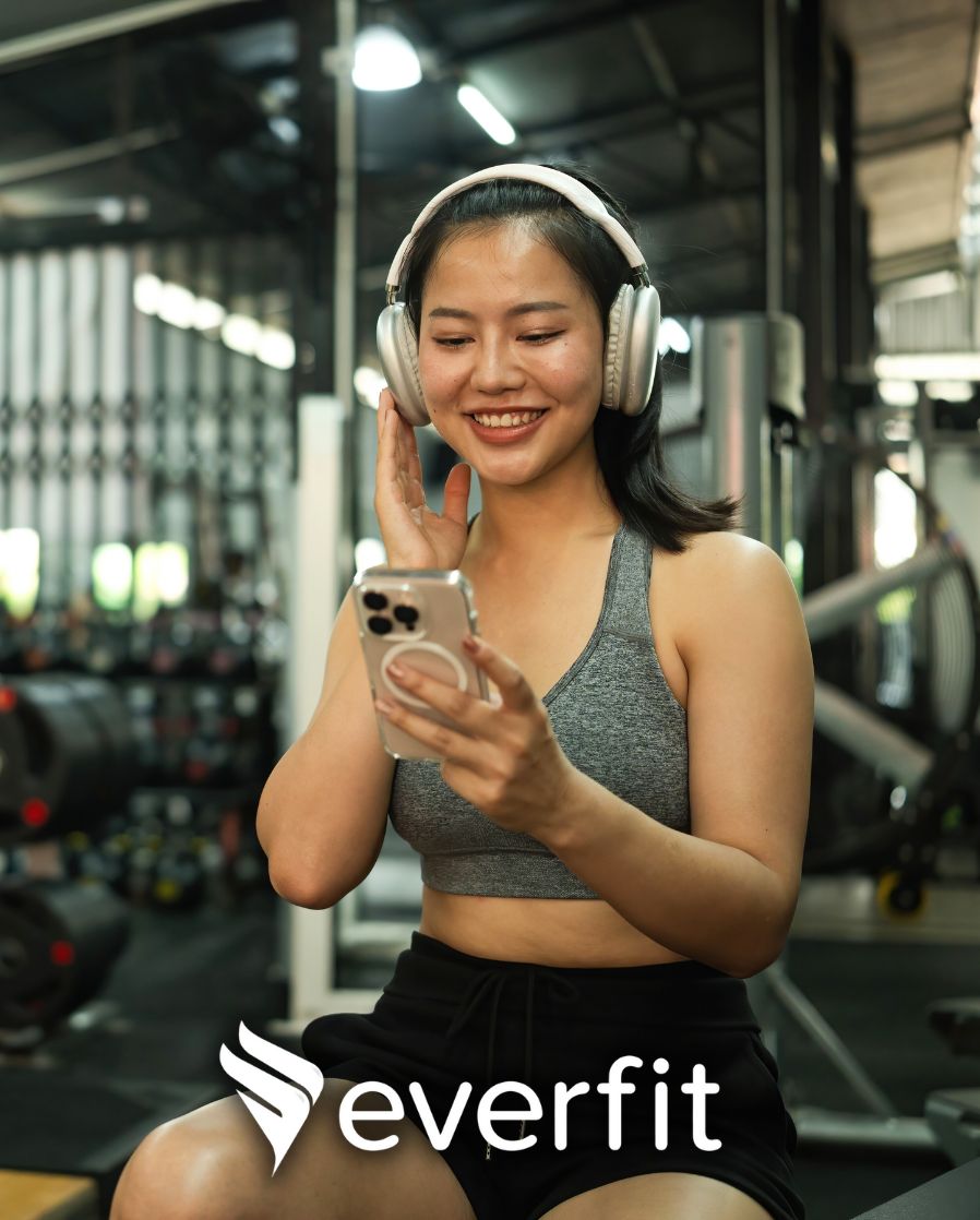 Female gym client reviewing her personalized workout program on the Everfit app, created by Coach Donovan.