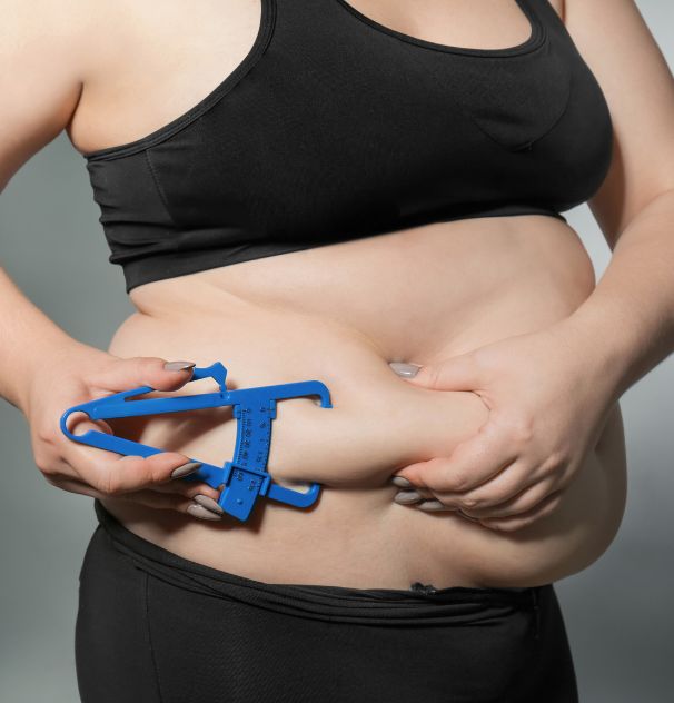 Woman measuring her body fat with a skinfold caliper to use the online body fat calculator from Coach Donovan.
